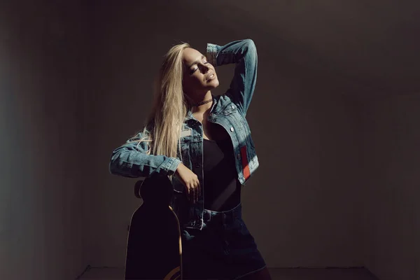 Hübsche blonde Frau mit Longboard im dunklen Raum — Stockfoto