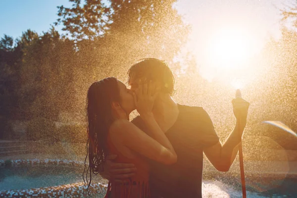 Pareja divirtiéndose se vierten entre sí con manguera de jardín — Foto de Stock