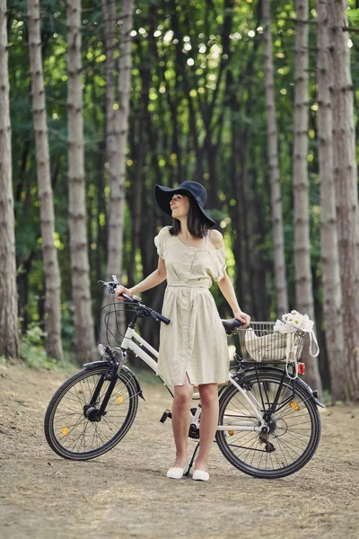 Jovem mulher contra a natureza fundo com bicicleta — Fotografia de Stock