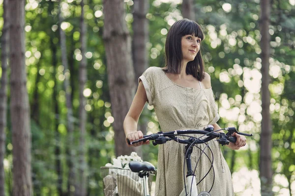 Jovem mulher contra a natureza fundo com bicicleta — Fotografia de Stock