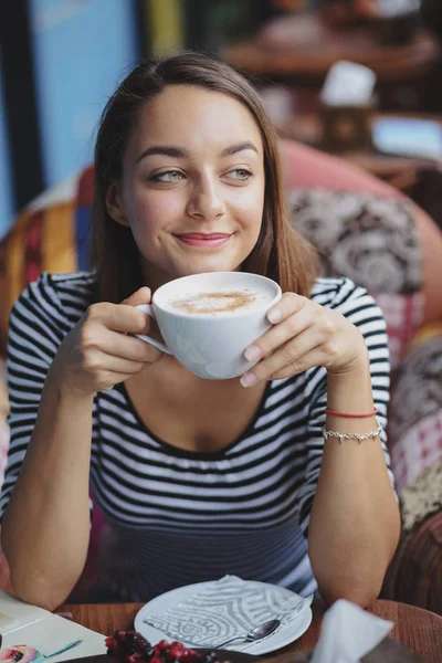 Молодая женщина сидит в помещении в городском кафе — стоковое фото