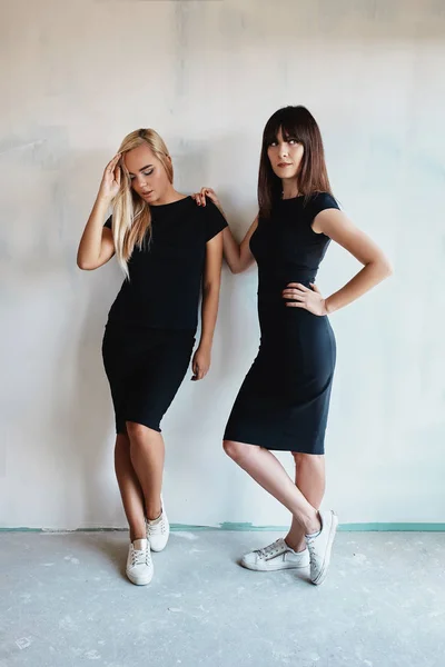 Dos mujeres guapas en un vestido negro interior — Foto de Stock