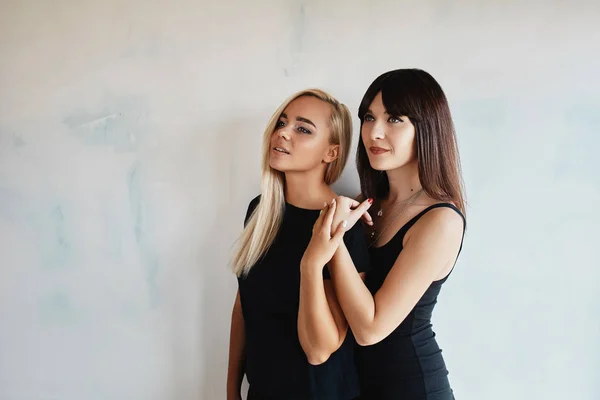 Dos mujeres guapas en un vestido negro interior — Foto de Stock