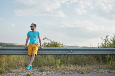 Gülümseyen ve güneşli yaz günü zevk genç adam