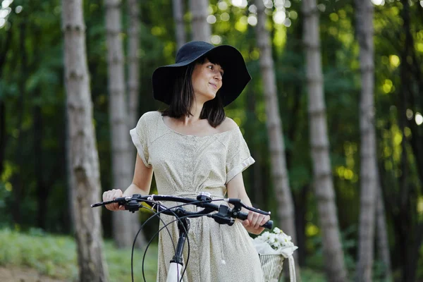 Jovem mulher contra a natureza fundo com bicicleta — Fotografia de Stock