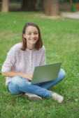 Fiatal nő laptop ül zöld fű