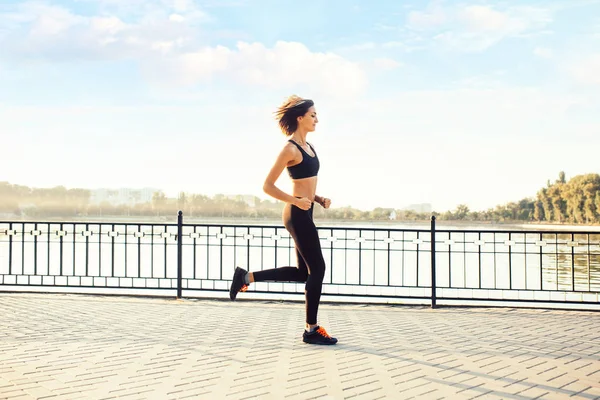 Woman running by the lake at sunset — Stock Photo, Image