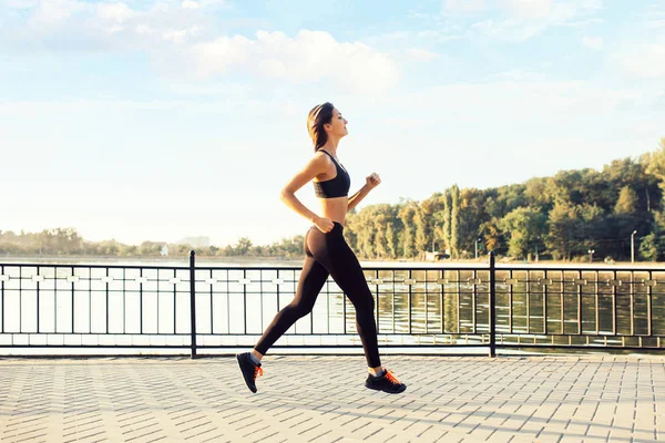 Woman running by the lake at sunset — Stock Photo, Image