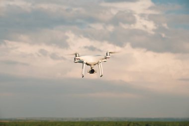 Beyaz dron açık mavi gökyüzünde süzülüyor