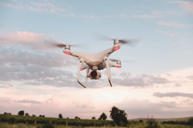 Beyaz dron açık mavi gökyüzünde süzülüyor