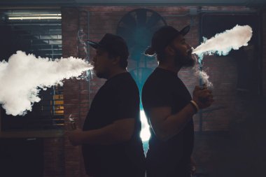 İki adam vaping tuğla duvarlı otantik bir odada