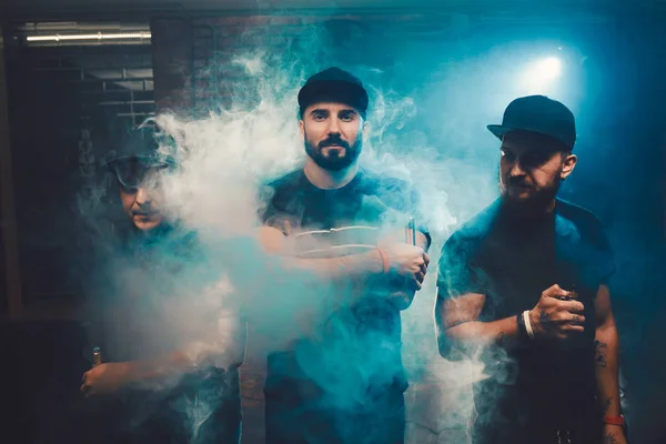 Três homens vaping em um quarto authentic com paredes de tijolo — Fotografia de Stock