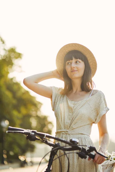 Retrato ao ar livre de jovem morena atraente em um chapéu em uma bicicleta . — Fotografia de Stock