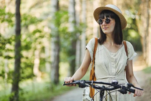 Außenporträt der attraktiven jungen Brünette mit Hut auf einem Fahrrad. — Stockfoto