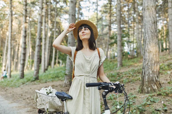 Außenporträt der attraktiven jungen Brünette mit Hut auf einem Fahrrad. — Stockfoto