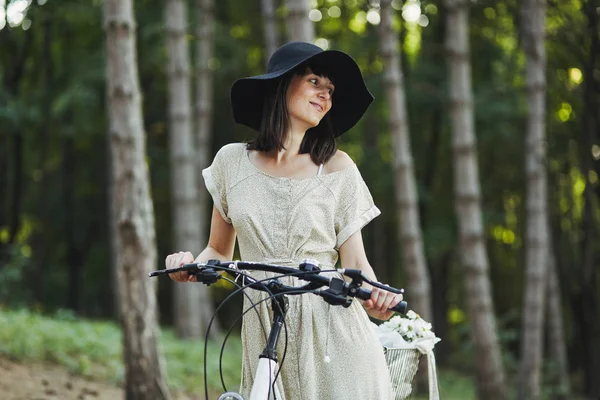 Plenerowej atrakcyjna młoda brunetka w kapeluszu na rowerze. — Zdjęcie stockowe