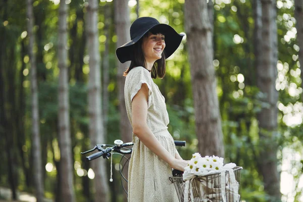 Außenporträt der attraktiven jungen Brünette mit Hut auf einem Fahrrad. — Stockfoto
