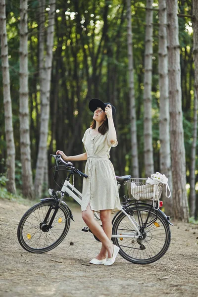 自転車を帽子で魅力的な若いブルネットの屋外のポートレート. — ストック写真