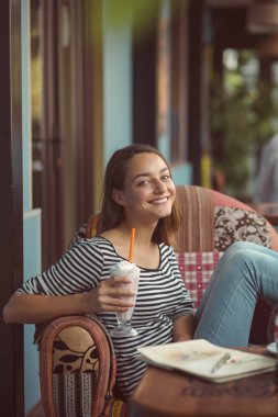 Bir kadın bir şehir Cafe yaz terasında oturur ve muzlu süt içiyor
