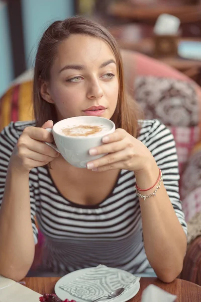 Junge Frau sitzt drinnen in urbanem Café — Stockfoto