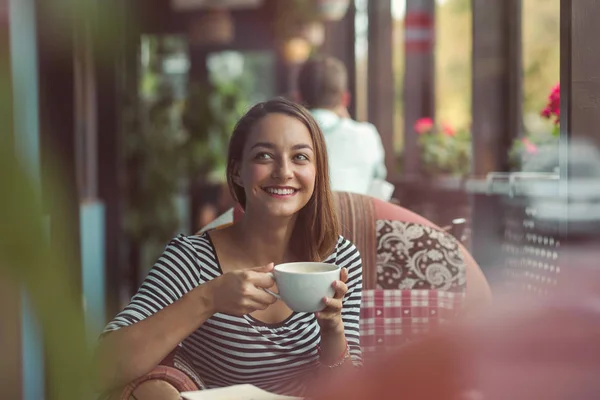 Giovane donna seduta al coperto in un caffè urbano — Foto Stock