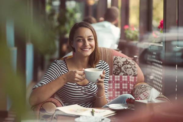 Junge Frau sitzt drinnen in urbanem Café — Stockfoto