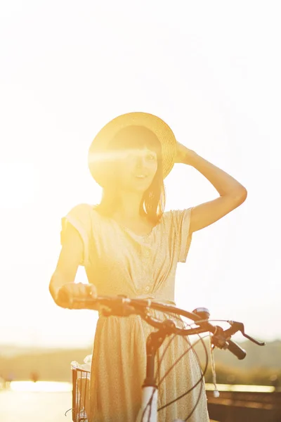 Retrato al aire libre de la atractiva joven morena en un sombrero en una bicicleta . — Foto de Stock