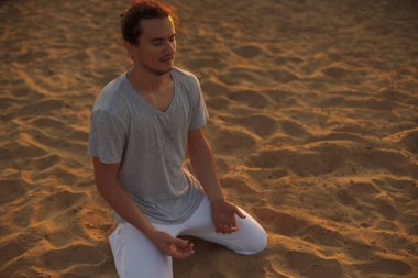 Yoga poz kum üzerinde duran sağlıklı genç adam vurdu.