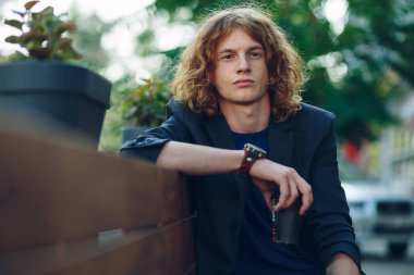 Kahve ile bankta oturan kırmızı saçlı hippi adam gitmek