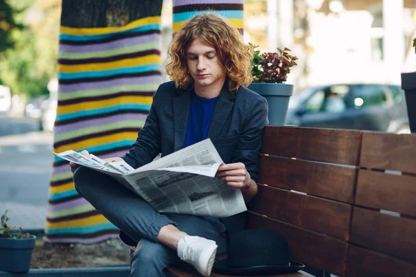 Rothaariger Hipster-Mann sitzt auf Bank und liest Zeitung — Stockfoto