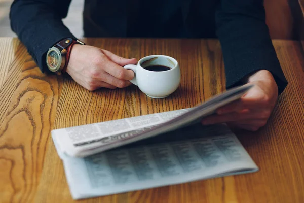 Mans mani primo piano in possesso di una tazza di caffè e un giornale — Foto Stock