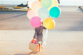 Dívka běží na schodech barevné balónky a childis