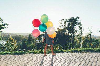 Renkli balonlar oynarken şehir parkında tutan kız,