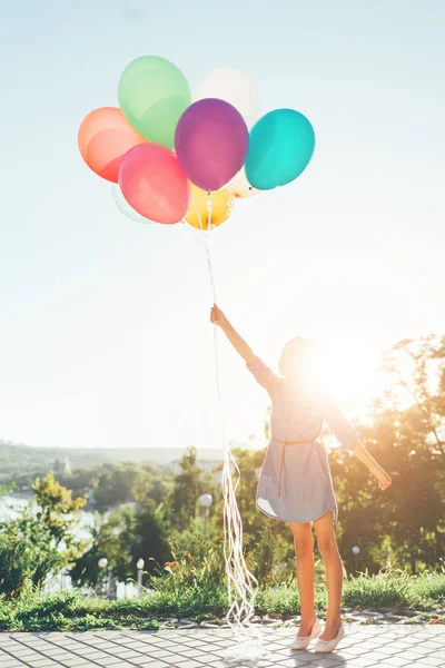 Dívka drží barevné balónky do nebe — Stock fotografie