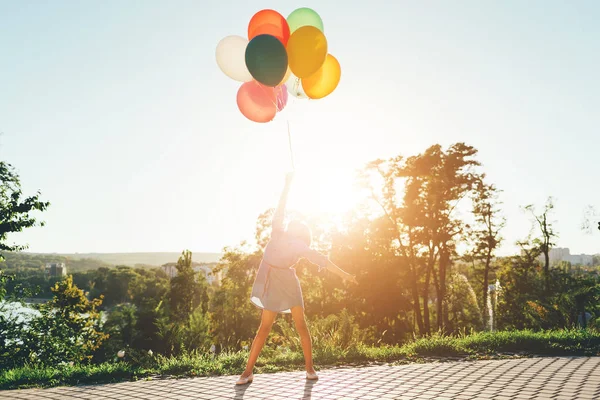 Söt flicka håller färgglada ballonger i city park, bor i — Stockfoto