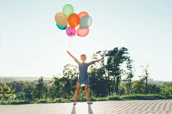 Милая девушка держит красочные воздушные шары в городском парке, играет — стоковое фото