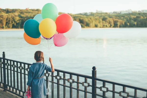 Zwiedzanie dziewczynka gospodarstwa kolorowe balony i dziecinna walizka — Zdjęcie stockowe