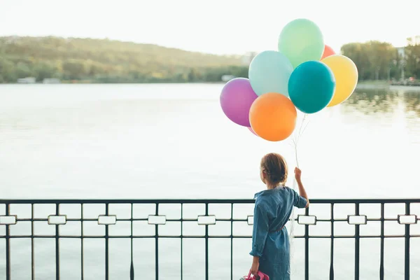 Veselá dívka drží barevné balónky a dětinské kufr l — Stock fotografie