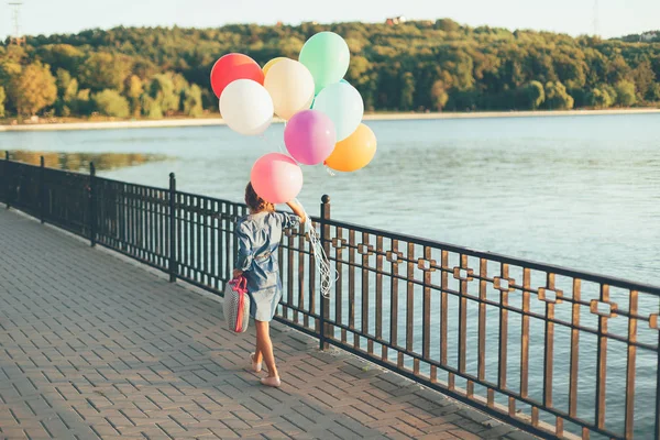Renkli balonlar ve çocukça bavul holding neşeli kız wa — Stok fotoğraf