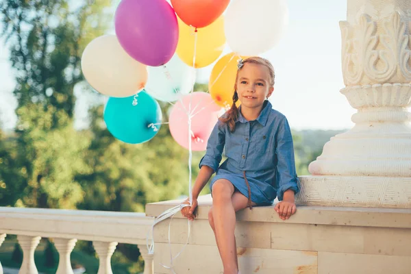 Retrato bonito menina segurando balões coloridos no parque da cidade — Fotografia de Stock