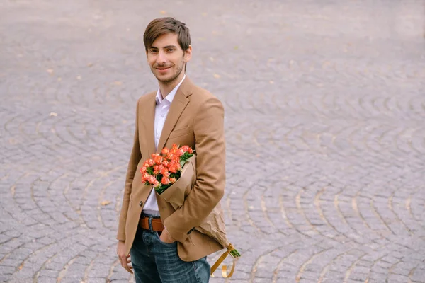 Portrét pohledný mladík s úsměvem držení Kytice růží — Stock fotografie