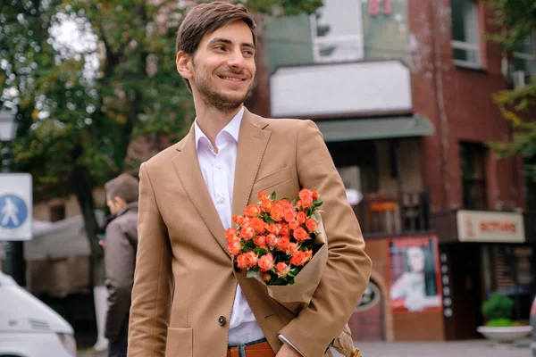 Portrait of young handsome man smiling holding a bunch of roses — Stock Photo, Image