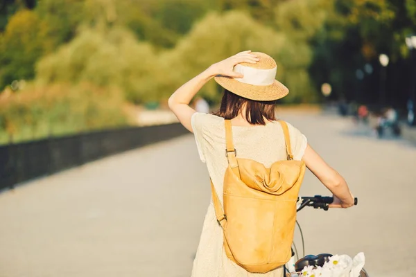 Retrato ao ar livre de jovem morena atraente em um chapéu em uma bicicleta . — Fotografia de Stock