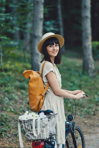 Außenporträt der attraktiven jungen Brünette mit Hut auf einem Fahrrad. — Stockfoto