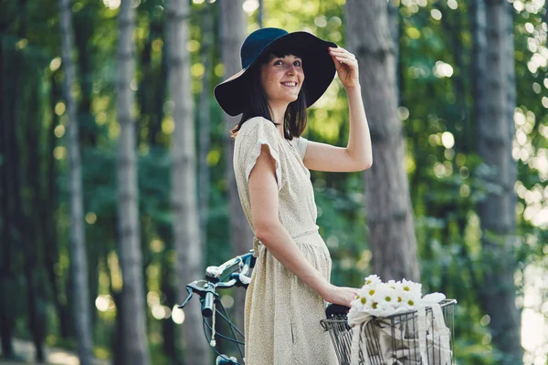 Jovem mulher contra a natureza fundo com bicicleta — Fotografia de Stock