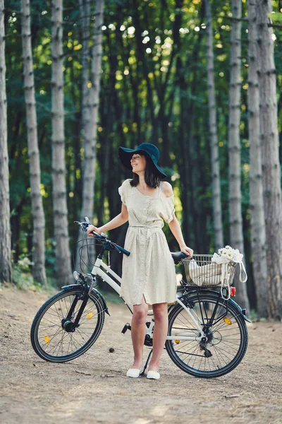 Jovem mulher contra a natureza fundo com bicicleta — Fotografia de Stock