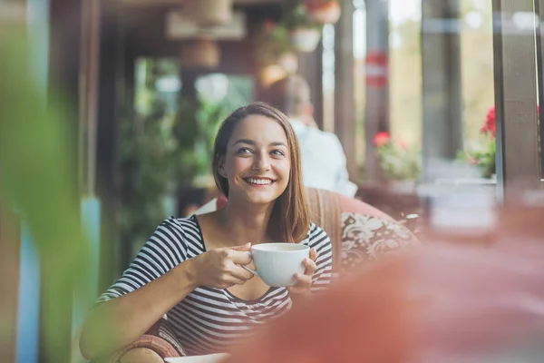 Junge Frau sitzt drinnen in urbanem Café — Stockfoto