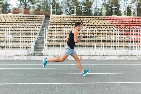 Joven atlético corriendo en el estadio por la mañana — Foto de Stock