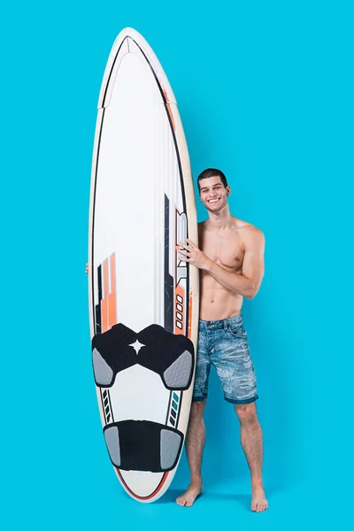 Surfista sonriente sosteniendo una tabla de surf — Foto de Stock