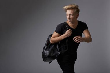 Omuzlarında bir sırt çantası ile çalışan yakışıklı genç